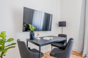 a dining room table with chairs and a tv on a wall at Apartment am Holländischen Viertel in Potsdam