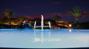 una gran piscina por la noche con palmeras en Camping Villaggio Pineta Al Mare, en Specchiolla