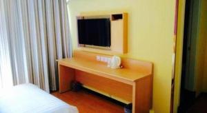 - une chambre avec un bureau et une télévision dans l'établissement 7 Days Inn Huanggang Luotian Hedong Street Dabieshan Food Plaza, à Luotian