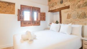 a bedroom with a white bed with a cross on it at Cárcel del Vicario by Toledo AP in Toledo +27 photos