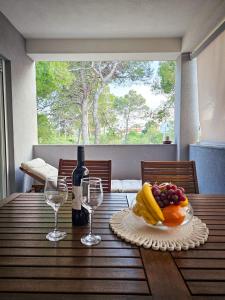 a table with a plate of fruit and a bottle of wine at Apartman TIA in Vir