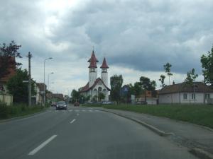 a car driving down a road in front of a church at Anca Apartment in Braşov