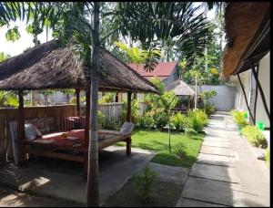 a pavilion with a bed and a straw umbrella at BATARA Homestay in Kuta Lombok