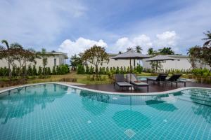 a pool with chairs and umbrellas next to a building at Caya Beach by Satori in Hinkong