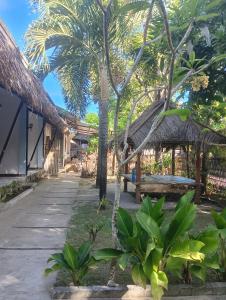 a resort with a bench and palm trees and a pathway at BATARA Homestay in Kuta Lombok