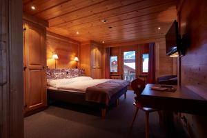 Schlafzimmer mit einem Bett, einem Schreibtisch und einem TV in der Unterkunft Hotel Landhaus in Gstaad