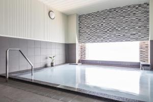La salle de bains est pourvue d'une grande baignoire et d'une fenêtre. dans l'établissement Hotel Vista Sendai, à Sendai