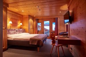 a bedroom with a bed and a desk and a television at Hotel Landhaus in Gstaad