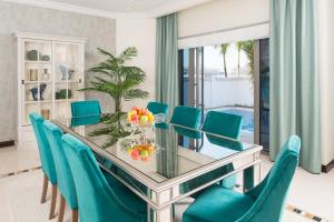 a dining room with a glass table and blue chairs at Nasma Luxury Stays - Frond L, Palm Jumeirah in Dubai