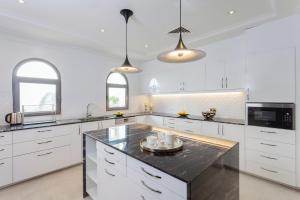 a kitchen with white cabinets and a black counter top at Nasma Luxury Stays - Frond L, Palm Jumeirah in Dubai