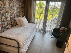 a bedroom with a bed and a chair and a window at B&B slapen in de veenhoop in De Veenhoop