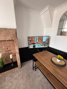 a living room with a wooden table and a fireplace at Corner Cottage in Derby