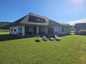 にあるFerienhaus Petzenblickの庭に3つの芝生の椅子が置かれた家