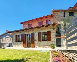 a stone house with wooden doors in a yard at Dama35 - Tuscany holiday house - Casentino-La Verna in La Verna
