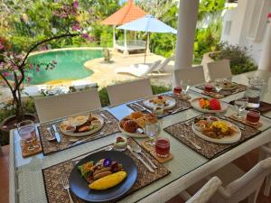 a table topped with plates of food next to a pool at Emerald Luxury & Comfort Villa in Nusa Dua in Nusa Dua