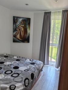 a bedroom with a bed and a painting on the wall at Апартамент Лятно изкушение in Balchik