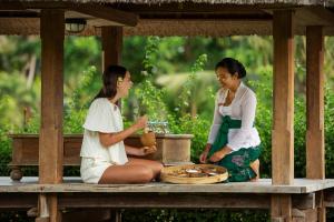 two women sitting on a picnic table talking at The Artini Dijiwa Ubud in Ubud
