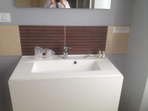 - un lavabo blanc dans la salle de bains avec une personne prenant une photo dans l'établissement Logis Hôtel Restaurant de France, à Isigny-sur-Mer
