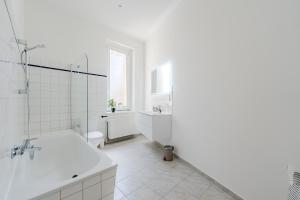 a white bathroom with a tub and a sink at Apartment am Holländischen Viertel in Potsdam