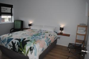 a bedroom with a bed and a chair and lamps at Hoki Boatshed Holiday Accommodation in Hokitika