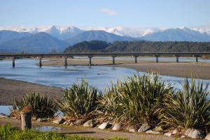 a bridge over a river with mountains in the background at Hoki Boatshed Holiday Accommodation in Hokitika +4 photos