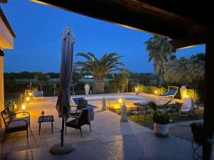 a patio with an umbrella and chairs and a pool at Domus Somnia in Fertilia