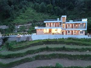 a large house on a hill with people standing in front of it at Yashasvi Himalayan Resort in Barmoāri