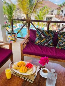 a table with a plate of food on a balcony at Sand Beach Boutique in Bwejuu