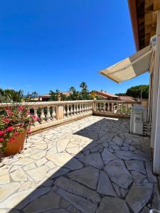 eine Steinterrasse mit einem Holzgeländer und einem Sonnenschirm in der Unterkunft Villa Les Terrasses de Giens in Hyères