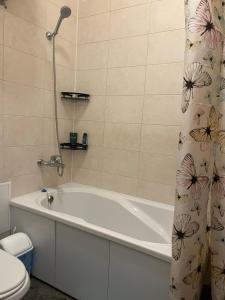ein Badezimmer mit einer Badewanne, einem WC und einem Duschvorhang in der Unterkunft Monro-style in the historical center in Odessa