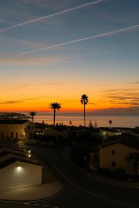 una puesta de sol sobre una calle con palmeras y el océano en La Cala de Mijas apartment, Sea View, 200m from the beach, close to town, en La Cala de Mijas