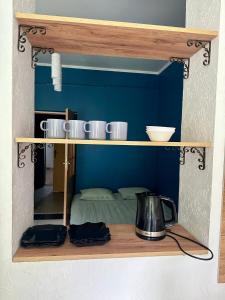 Un estante con cuatro tazas y una tetera encima. en Guculka, en Yaremche