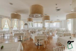 a restaurant with white tables and chairs and large windows at HOTIDAY Room Collection - Mattinata Faraglioni in Mattinata