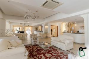 a living room with two white couches and a kitchen at HOTIDAY Room Collection - Mattinata Faraglioni in Mattinata