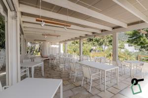 a patio with white tables and white chairs at HOTIDAY Room Collection - Mattinata Faraglioni in Mattinata