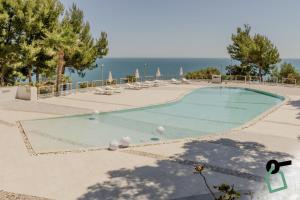 a swimming pool with chairs and the ocean in the background at HOTIDAY Room Collection - Mattinata Faraglioni in Mattinata