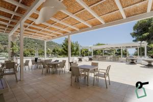 an outdoor patio with tables and chairs and a roof at HOTIDAY Room Collection - Mattinata Faraglioni in Mattinata