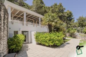 a white house with a palm tree and bushes at HOTIDAY Room Collection - Mattinata Faraglioni in Mattinata