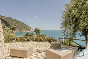 a patio with chairs and a view of the ocean at HOTIDAY Room Collection - Mattinata Faraglioni in Mattinata