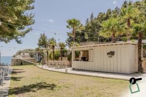 a small white building with trees and the ocean in the background at HOTIDAY Room Collection - Mattinata Faraglioni in Mattinata