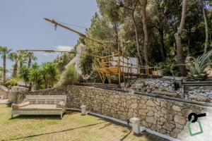a garden with a stone wall and a bench at HOTIDAY Room Collection - Mattinata Faraglioni in Mattinata