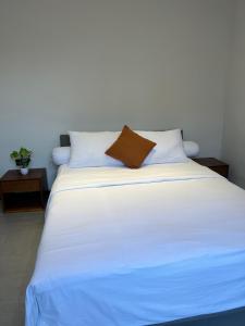 a large white bed with a brown pillow on it at Villa Mecca in Batu +9 photos