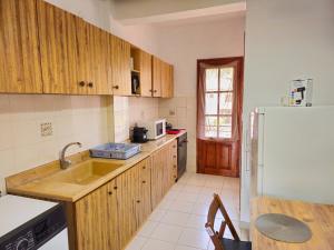 a kitchen with wooden cabinets and a white refrigerator at Idyllic Escape Apartment in Gomátion