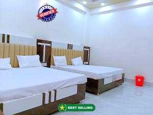 范兰德凡Hotel Dev Shri Residency ! near Prem mandir & ISCKON ! Fully AC rooms ! Café & Banquet, Free parking & Lift availability的墙上有标牌的房间的两张床