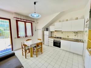 a kitchen with white cabinets and a table with chairs at Bilocali del Sole in Marina di Bibbona +39 photos
