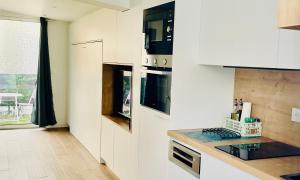 a kitchen with white cabinets and a stove top oven at Rez de Jardin - Calme & Familiale in Varreddes