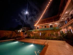 ein Schwimmbad vor einem Gebäude bei Nacht in der Unterkunft 12 Monks - Backpacker Resort in Arambol