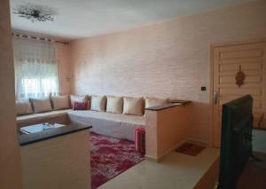 un soggiorno con un divano e un tavolo di Appartement confortable en face du complexe scolaire newton a Kenitra