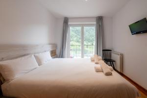 a bedroom with a large white bed with a window at Barthe Holidays I Acogedor apartamento en Arinsal 6PAX a pie de pistas I Balcón con vistas y parking I Madness in Arinsal