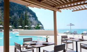 a patio with tables and chairs next to a pool at Ella Alkyna - Adults Only in Agios Gordios